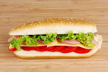 Sandwich with sausage, cheese and tomatoes on wooden background