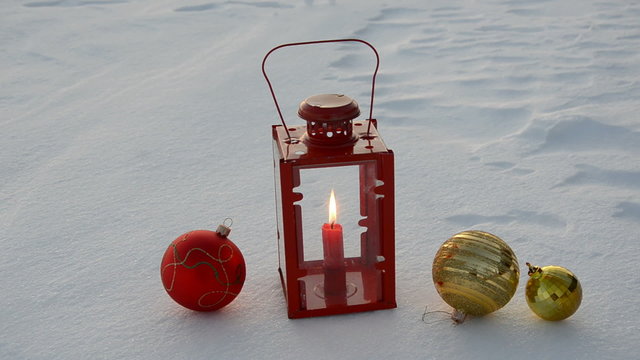 christmas balls and lamp with candle on winter snow