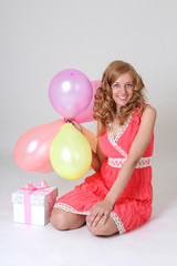 Obraz na płótnie Canvas Sitting in balloons birthday girl with gift