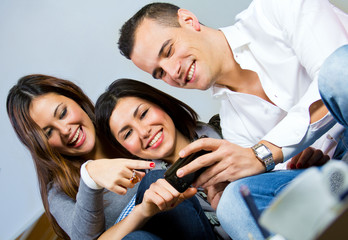 Obraz premium three friends having fun with a mobile phone