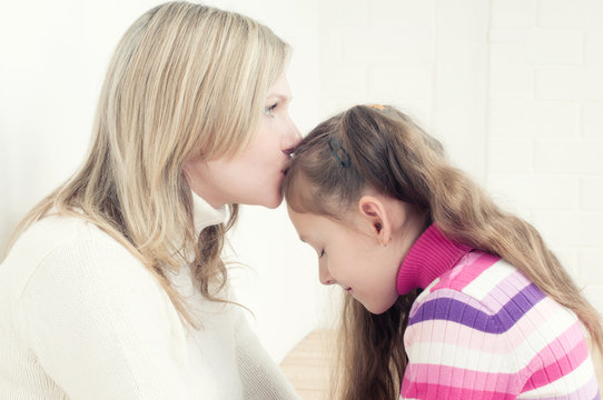 Young caucasian woman kissing her little daughter