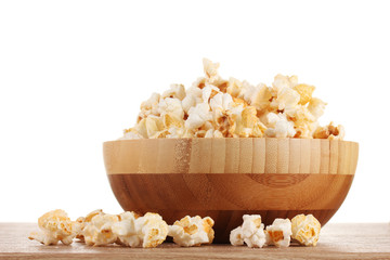 popcorn in wooden bowl on wooden table on white background