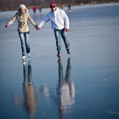 Couple ice skating outdoors on a pond on a lovely winter day