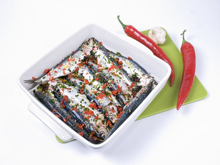 Teglia di sarde con peperoncino, aglio prezzemolo da infornare su sfondo bianco