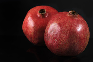 Two ripe pomegranates on black background