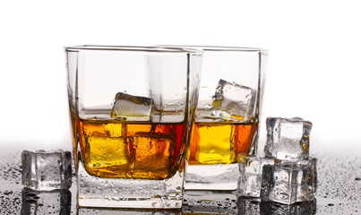 two glasses of scotch whiskey and ice on table isolated on white