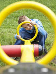 young boy looking through of yellow circle on the playground