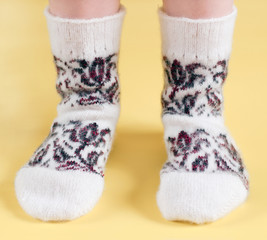 Children's feet in wool socks on a yellow background