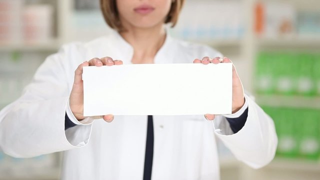 apothekerin zeigt wei&szlig;es schild