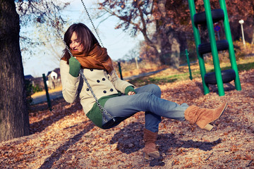 Autumn portrait of a young woman on a swing - obrazy, fototapety, plakaty