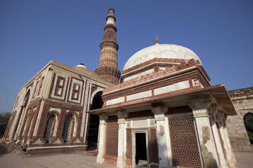 Fototapeta premium Indian temple with a tomb and Qutub minar tower at the back
