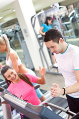 Fototapeta na wymiar personal trainer encouraging man using treadmill