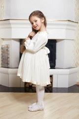 smiling girl in white dress  at home touching her dress