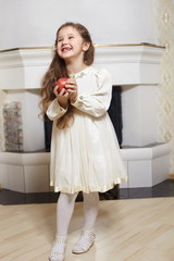 young smiling girl in white dress posing with red apple