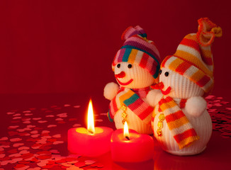 Two snowmen with two burning heart shaped candles