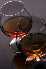 Two glasses of cognac on grey background closeup