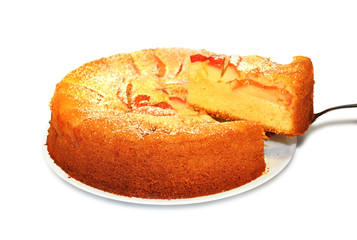 Slice of homemade apple pie on spatula with whole pie on white i