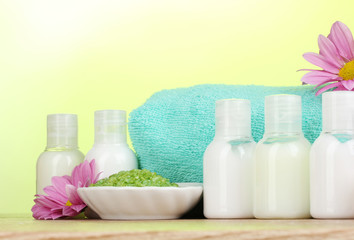 Hotel amenities kit on wooden table on green background
