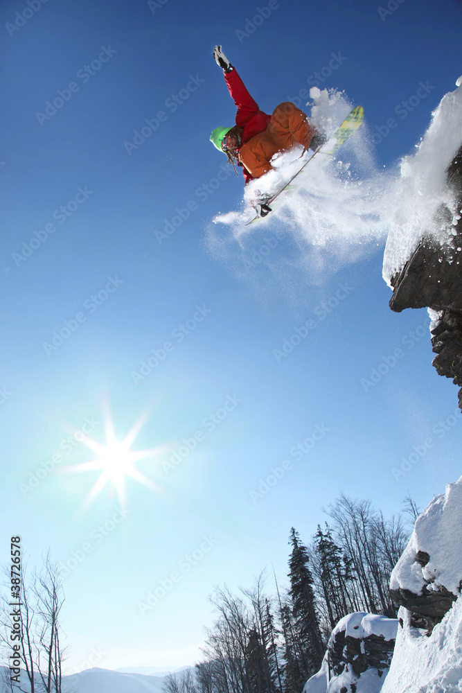 Wall mural Snowboarder jumping against blue sky