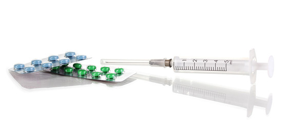 Syringe and tablets isolated on white
