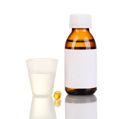 Medical bottle with jigger and tablets isolated on white