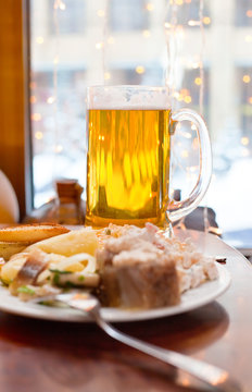 The big mug of beer and cold dishes on a little table at restaur