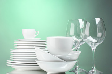 Clean plates, cups and glasses on green background