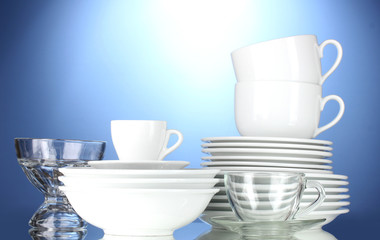empty bowls, plates, cups and glasses on blue background