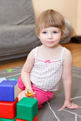 Portrait of small girl playing with bricks on floor