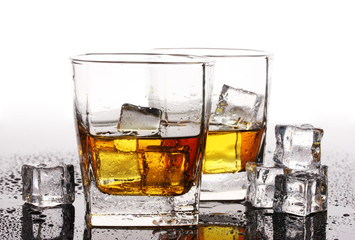 two glasses of scotch whiskey and ice on table isolated on white
