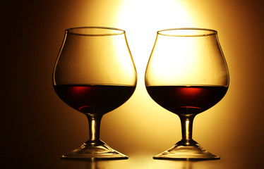 Two glasses of cognac on yellow background