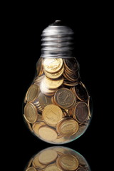 Traditional glass bulb with many golden coins on black