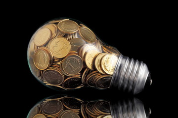 Traditional glass bulb with many golden coins on black