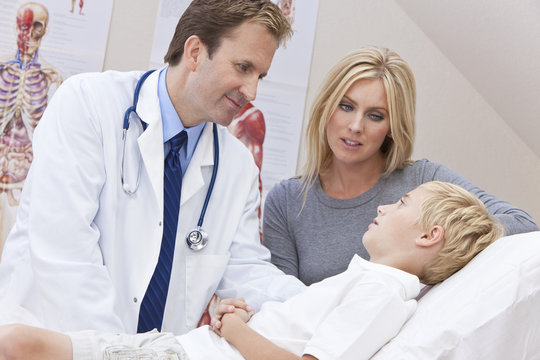 Male Doctor Examining Boy Child With Mother In Hospital