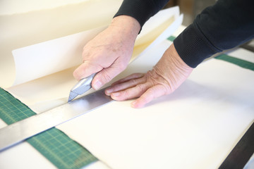 man cutting art paper with ruler and box cutter