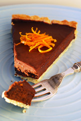 An orange chocolate tart with a fork on a blue plate