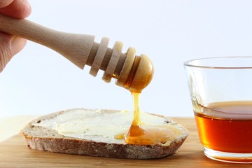 hölzerner Honiglöffel Honig fließt auf Brot