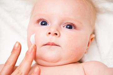 Mother creaming cute infant girl face
