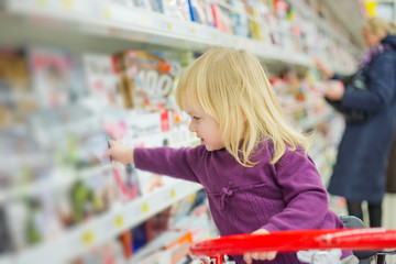 Little girl at magazines section in supermarket