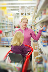 Mother and daughter in baby food section in supermarket