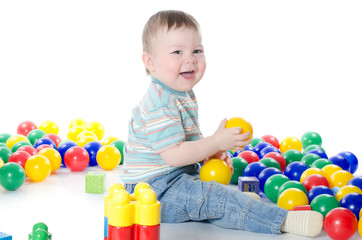 Fototapeta na wymiar The little boy plays multi-coloured toys