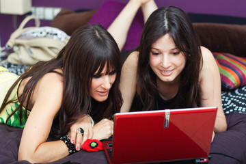 two young female friends having fun with laptop computer