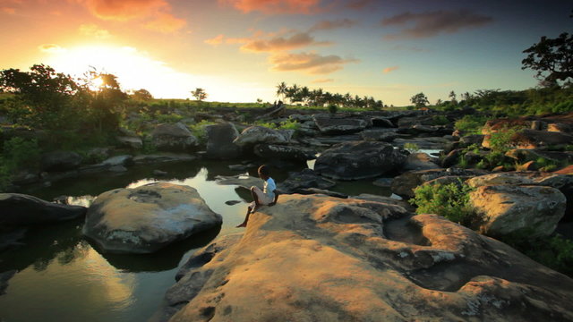 Child sitting on a rock in Kenya at sunset.