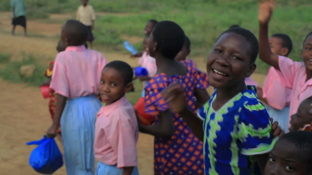 Children running alongside a car, smiling in Kenya, Africa.