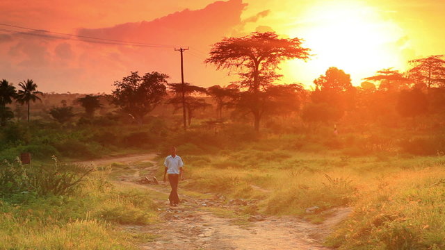 School boy walking in Kenya with beautiful sunrise sunset.