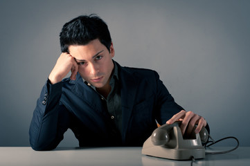 Man waiting for a phone call against grey background.