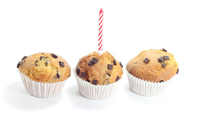 three chocolate muffins with a candle