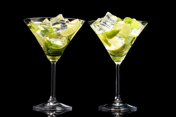 glasses of cocktails with lime and mint on black background