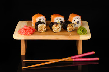 Tasty rolls served on wooden plate isolated on black