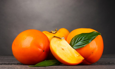 Appetizing persimmons on wooden table on grey background